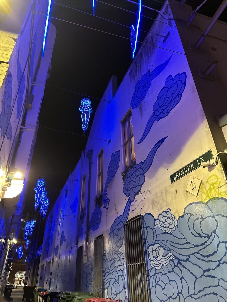 Glowing blue neon art and mural on a Chinatown laneway wall